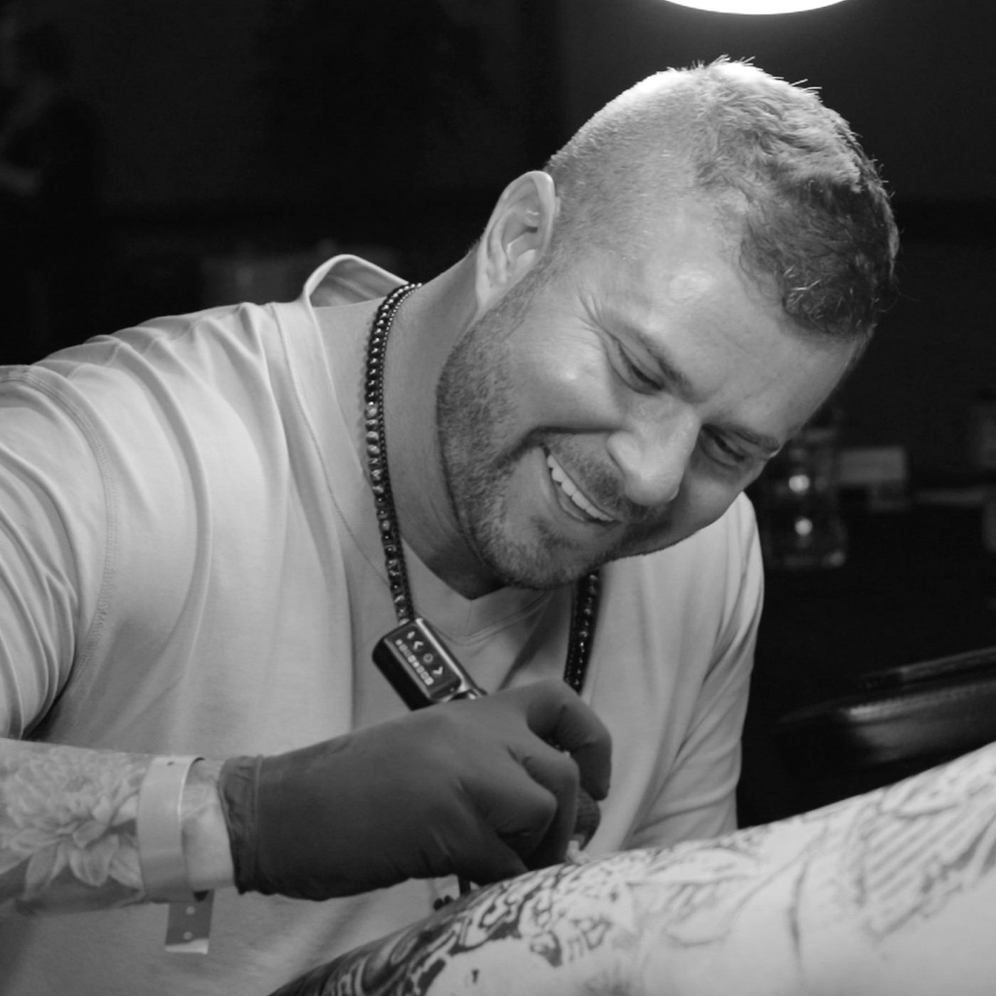 Bubba Irwin tattooing a client — black and white candid photo