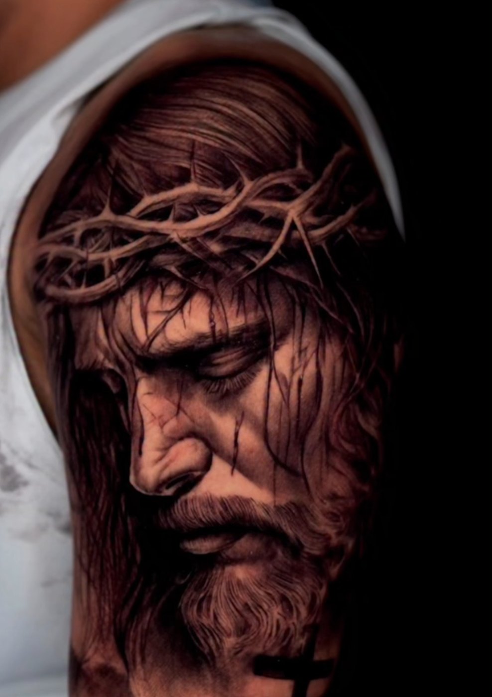 Hyper-realistic black and grey Jesus portrait tattoo with crown of thorns