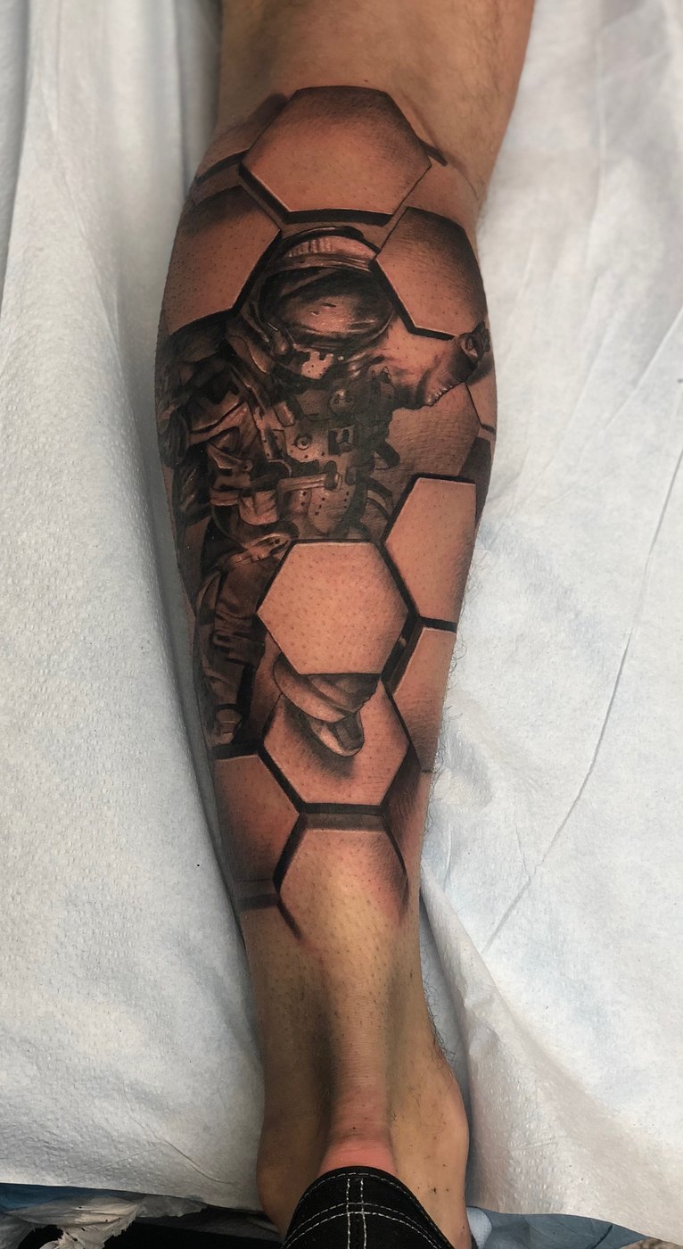 Astronaut and honeycomb black and grey calf tattoo by Ink Master Bubba Irwin, geometric realism